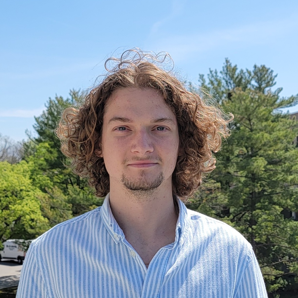 Photo of Cole standing outside in front of a tree