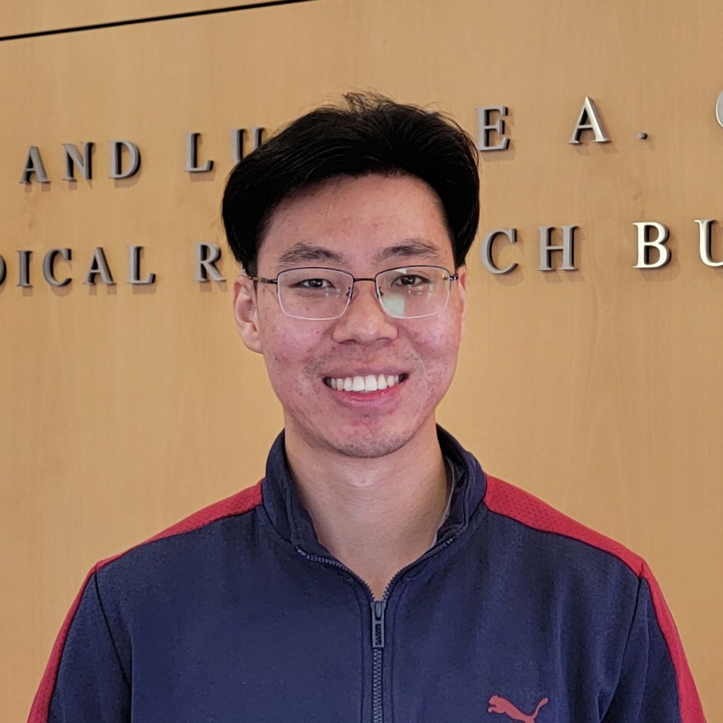 Photo of Daniel standing in front of a wood panel wall